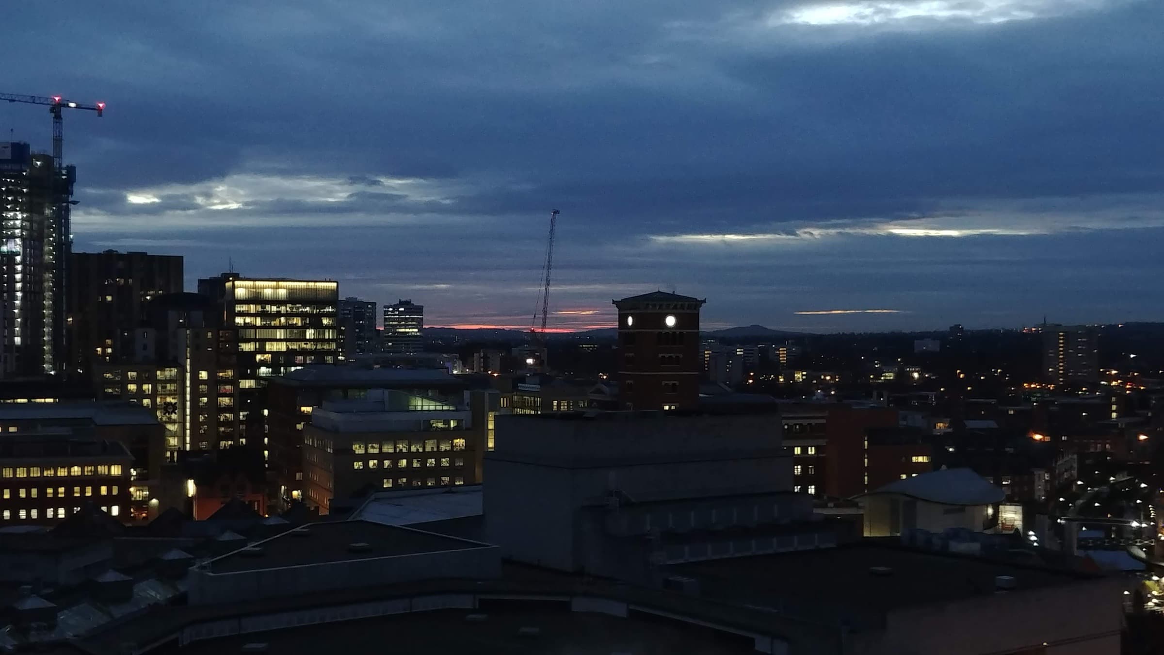 Birmingham city centre skyline at dusk with illuminated buildings and the Old Joe clock tower