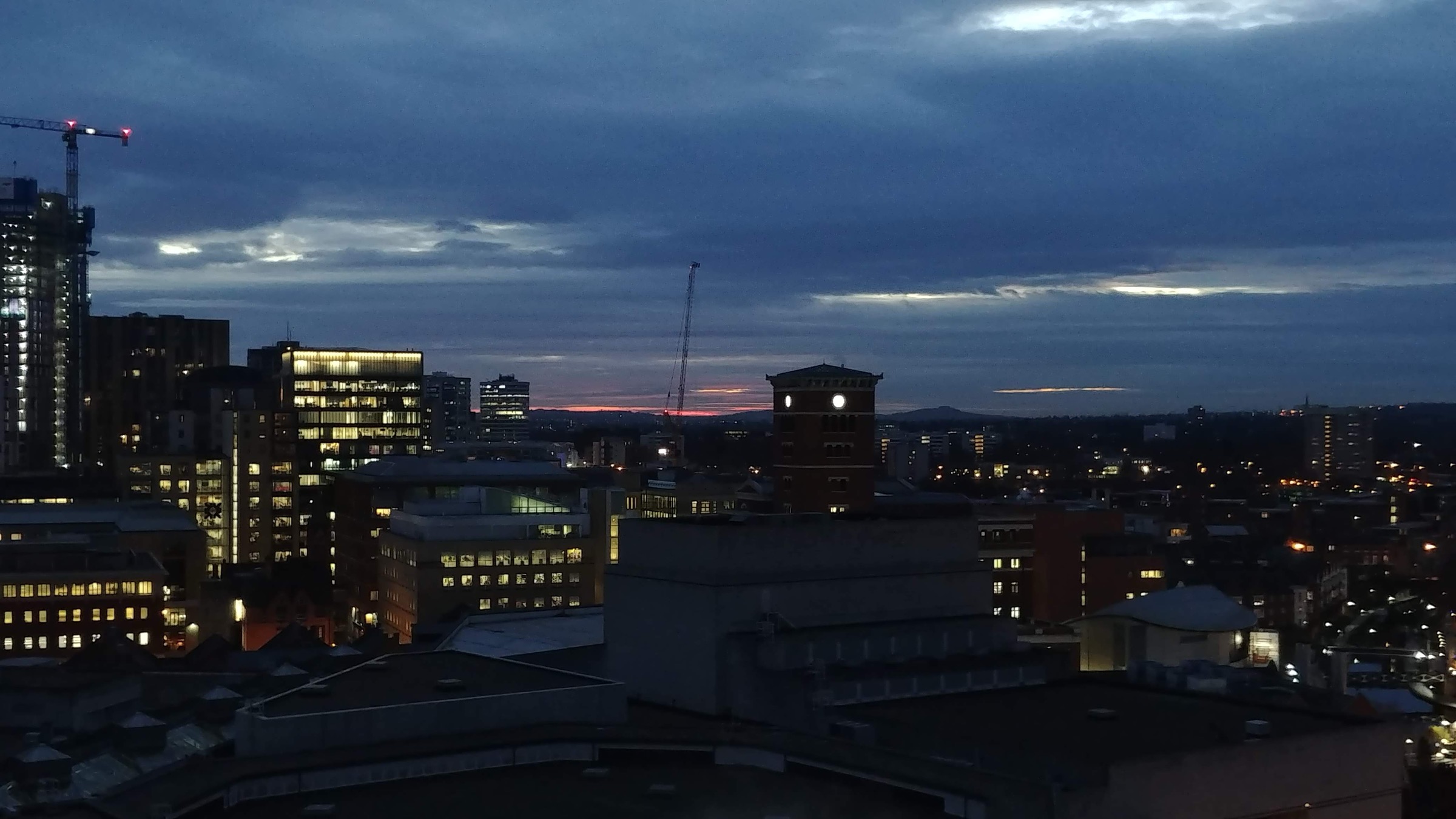Birmingham city centre skyline at dusk with illuminated buildings and the Old Joe clock tower